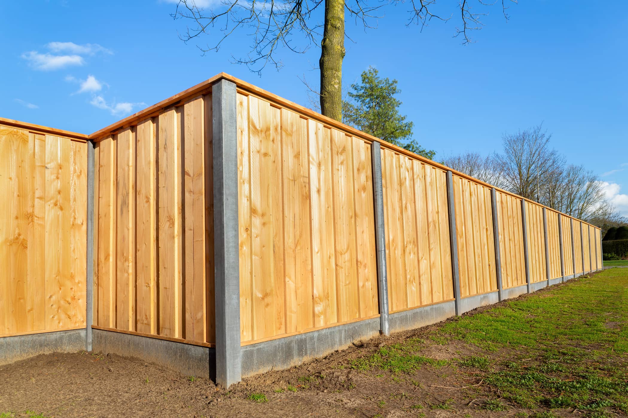 This image shows a fence that is made of both wood and concrete for extra support.